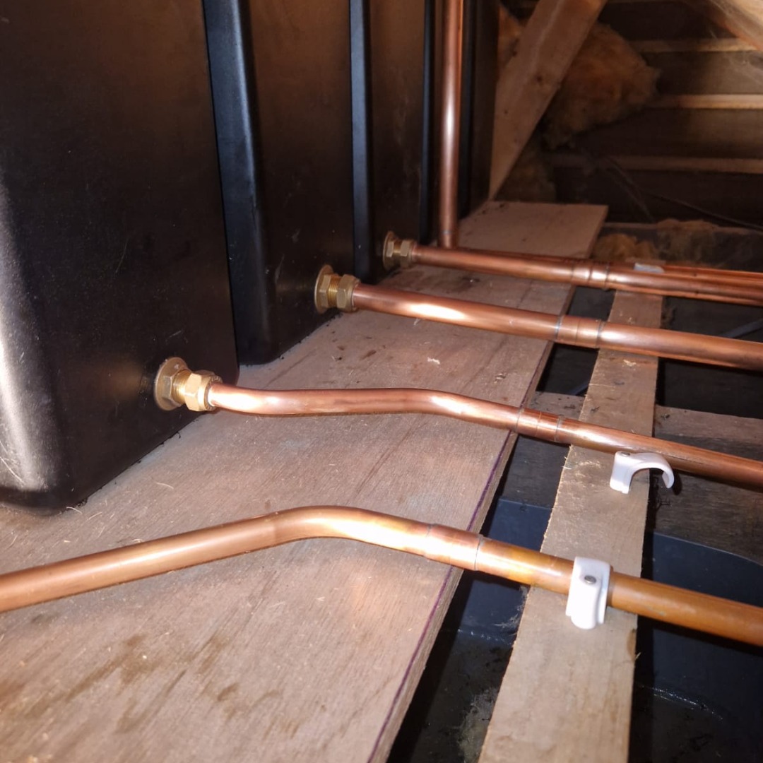 New copper pipework run across the joists in a loft